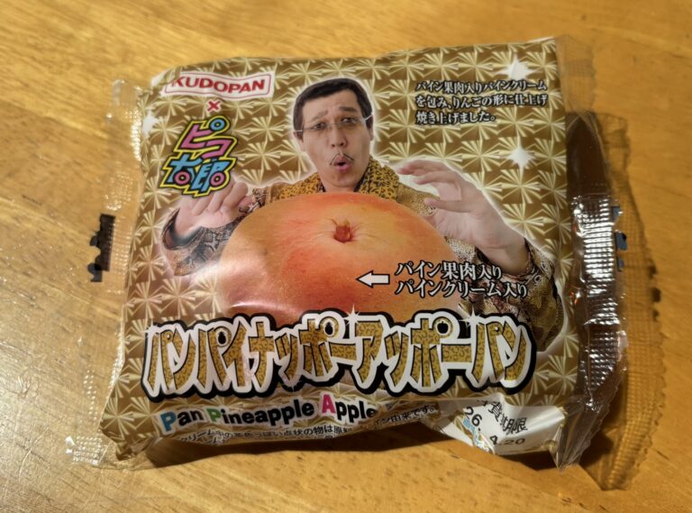 A packaged Pan Pineapple Apple Pan, a collaboration bread by Kudo Pan and Pikotaro, placed on a wooden table.