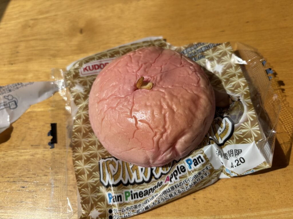A pink apple-shaped bread from Kudo Pan’s Pan Pineapple Apple Pan, with a small stem-like detail on top.