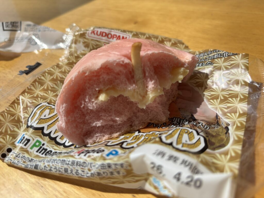 A cut-open Pan Pineapple Apple Pan showing pineapple cream inside the pink apple-shaped bread.