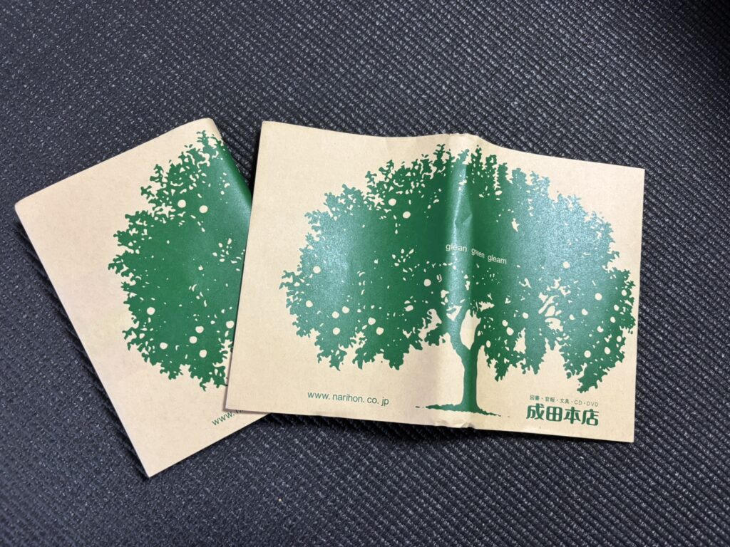 A brown Narita Honten bookstore cover with a green tree design.