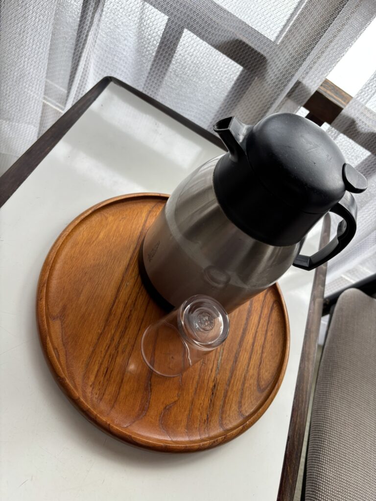 A water pot and glass on a small table by the window in a traditional room at Sukayu Onsen.